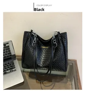 Detail of black woven texture on tote bag with silver chain strap and logo plaque