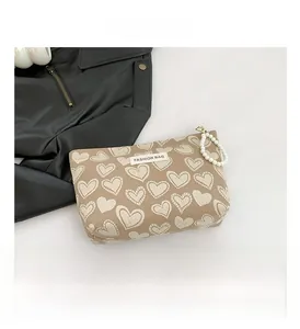 Detail of khaki heart-patterned canvas mini bag with decorative faux pearl strap
