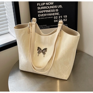 Detail of off-white PU leather tote bag with silver butterfly metal ornament and texture