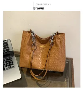 Detailed texture of brown woven PU leather tote bag with elegant silver chain shoulder straps