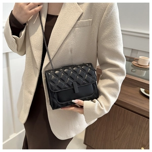 Détail d'un sac à bandoulière matelassé noir avec chaîne et fermoir sur un mannequin