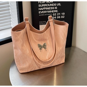 Pink velvet tote bag with silver butterfly detail on an industrial metal table
