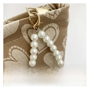 Detail of canvas phone bag with heart prints and elegant pearl bead handle