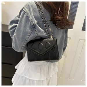 Fashionable black quilted chain crossbody bag for women worn with casual denim jacket