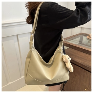 Detailed view of beige soft leather hobo bag with cute plush bear charm accessory