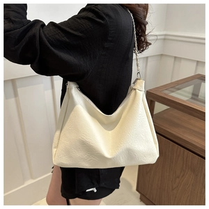 Detail of cream white leather underarm bag featuring natural pleated texture and chain strap