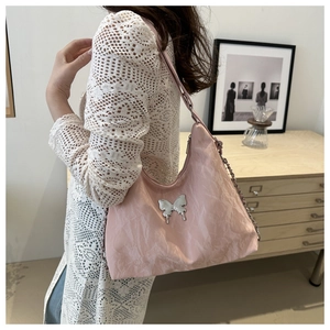 Pink pleated crossbody bag with silver butterfly charm detail on textured fabric