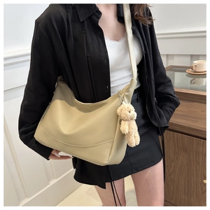 Detail of beige crescent shoulder bag with matte leather finish and cute bear charm