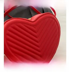 Detailed view of red heart-shaped bag with chevron quilting and golden zipper detail