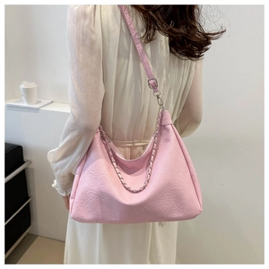 Close-up of pink ruched shoulder bag with silver chain strap shown on a model