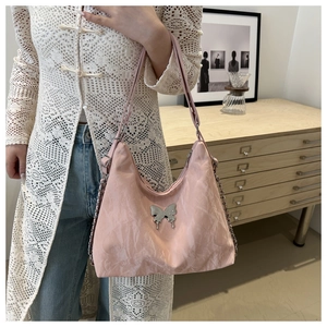 Detailed view of pink textured crossbody bag with silver butterfly metal ornament