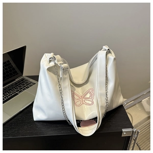 Detail of white leather tote with pink butterfly embroidery and heart pendant