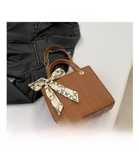 Close-up of brown quilted tote bag with silk scarf handle and gold chain strap details