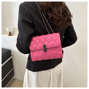 Detail view of pink quilted crossbody bag with silver chain strap on model's shoulder