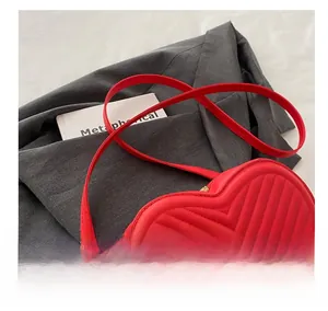 Detail of red heart-shaped bag featuring elegant V-quilting and adjustable strap hooks