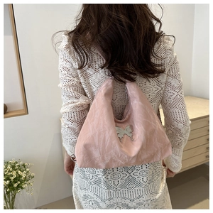 Close-up of pink pleated hobo bag with silver butterfly metal buckle and soft texture
