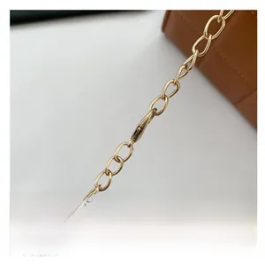 Detailed close-up of the golden metal chain and clasp on the quilted shoulder bag