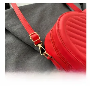 Detail of red quilted leather bag showing golden metal buckle and lobster clasp