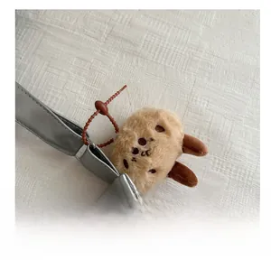 Detail of a brown plush cartoon dog charm with matching beads on a metal strap