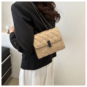 Détail du sac bandoulière beige matelassé avec chaîne noire et boucle en métal mat