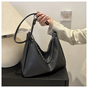 Detail of minimalist black leather hobo bag with silver chain strap and matte texture