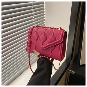 Detail of rose pink wave quilted texture and gold chain strap on small shoulder bag