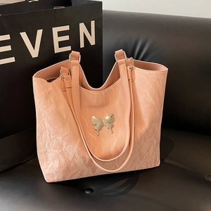 Pink velvet-textured tote bag with metal butterfly ornament and double shoulder straps