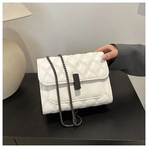 Détail du sac blanc matelassé avec surpiqûres en losange et bandoulière chaîne noire