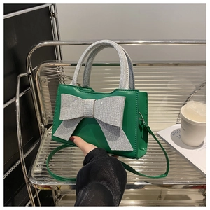 Détail d'un sac à main en cuir vert avec un grand nœud en strass argentés étincelants