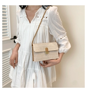 Detail of woven straw shoulder bag with gold metal buckle and elegant chain strap