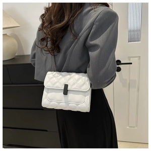 Détail d'un sac bandoulière blanc matelassé avec fermoir noir et bandoulière chaîne