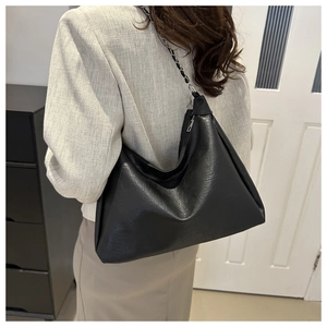 Detail of black hobo bag with pleated leather texture and chain woven shoulder strap