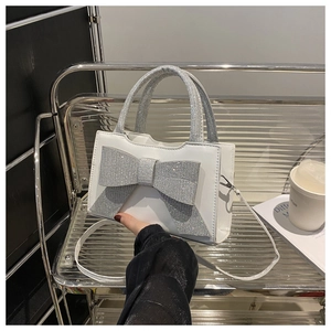 Détail du sac à main blanc orné d'un grand nœud en strass argentés et d'une poignée