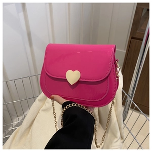 Detail of bright pink patent leather handbag with a golden heart-shaped metal buckle