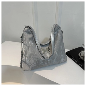 Detail of silver pleated texture tote bag with metallic butterfly and chain strap
