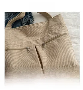 Detail view of the beige corduroy tote bag showing dual vertical metal zipper pockets