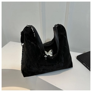 Detail of black velvet tote bag with metallic butterfly accent and silver chain strap