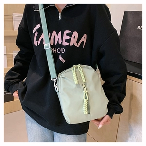 Détail du sac bandoulière en nylon vert menthe avec fermeture éclair et pendentif tissé jaune