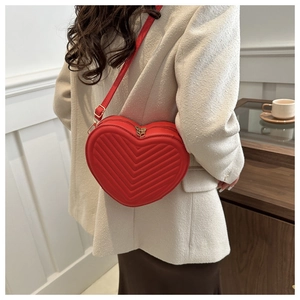 Detail of red heart-shaped crossbody bag with elegant V-shaped quilting and zipper
