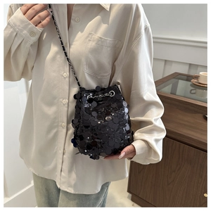 Nahaufnahme einer schwarzen Pailletten-Beuteltasche mit Metallkette und Kordelzug