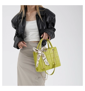 Close-up of neon green quilted tote bag with golden chain strap and decorative scarf