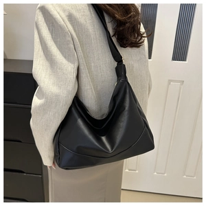 Detail of minimalist black faux leather shoulder bag with soft pleats for commuters