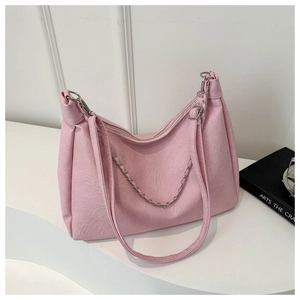 Detail of pink PU leather handbag with metal chain and textured finish on a white surface