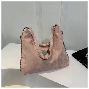 Close-up of pink pleated bucket bag featuring a silver metal butterfly ornament