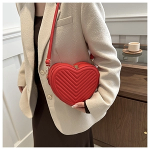 Close-up of red heart-shaped leather crossbody bag with elegant V-shaped quilting detail
