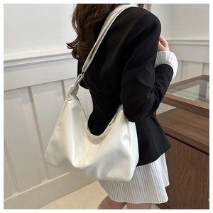Detail view of a white leather hobo bag showing soft texture and wide shoulder strap