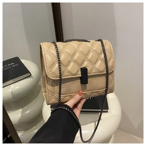 Détail du sac bandoulière beige matelassé avec fermoir noir et chaîne métallique