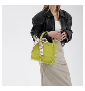 Detail of quilted bright yellow handbag featuring printed silk scarf and gold chain strap