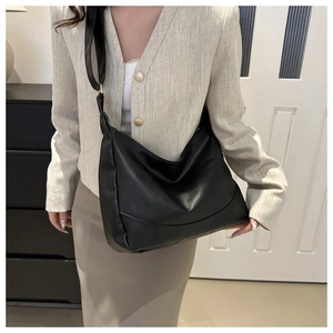 Detail showing spacious black faux leather hobo bag with a wide shoulder strap on model