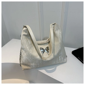 Detail of cream tote bag with marble texture fabric, silver butterfly and chain strap